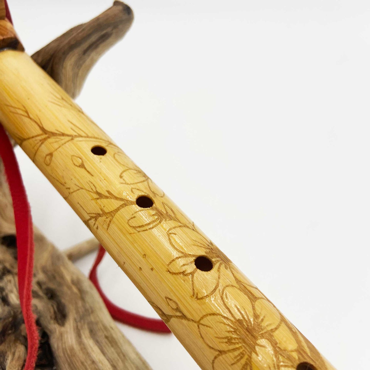 Flûte amérindienne en bambou gravée de fleurs de cerisier, avec totem en bois d’olivier et lacet rouge, accordée en La 432Hz.
