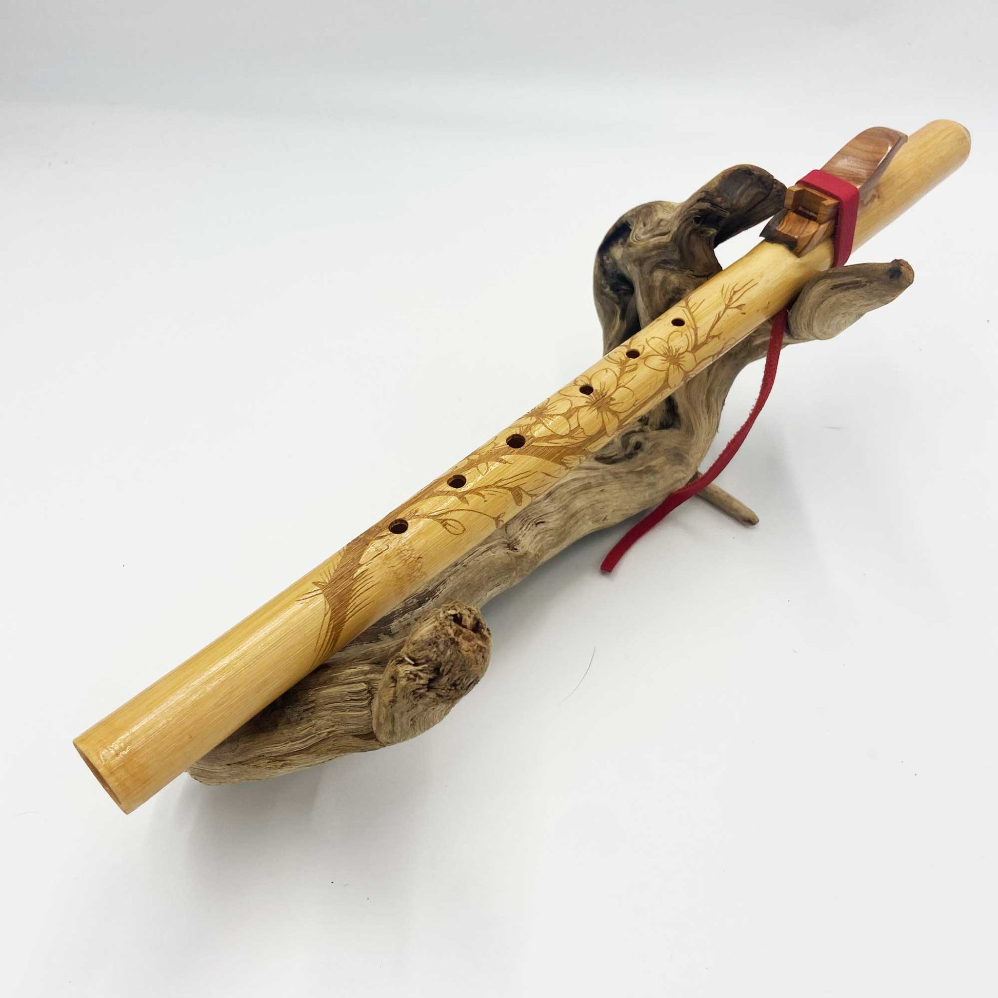 Flûte amérindienne en bambou gravée de fleurs de cerisier, avec totem en bois d’olivier et lacet rouge, accordée en La 432Hz.
