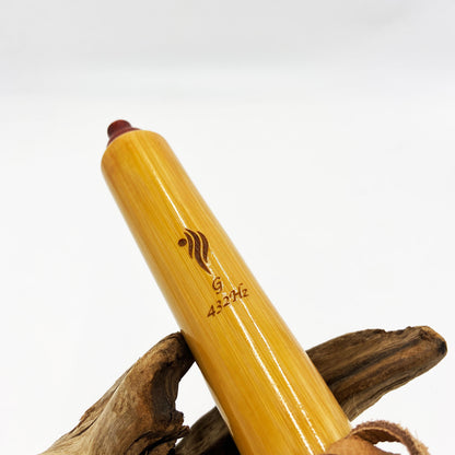 Flûte amérindienne professionnelle en bambou brillant (Shellawax), accordée en Sol 432Hz. Focus sur le totem sculpté en padouk et l'embouchure ergonomique. Instrument de concert.
